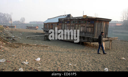 Srinagar, Indiano Kashmir amministrato: 29 dicembre un kashmir uomo cammina in tra il fiume Jhelum vicino Houseboats galleggiante sul parzialmente essiccato dopo le inondazioni Devasting hits valle del Kashmir migliaia di case danneggiate e centinaia di morti (©Sofi Suhail/Alamy Live News ) Foto Stock