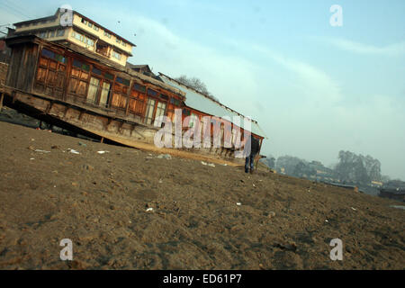 Srinagar, Indiano Kashmir amministrato: 29 dicembre un kashmir uomo cammina in tra il fiume Jhelum vicino Houseboats galleggiante sul parzialmente essiccato dopo le inondazioni Devasting hits valle del Kashmir migliaia di case danneggiate e centinaia di morti (©Sofi Suhail/Alamy Live News ) Foto Stock