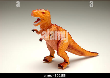 Dinosauro giocattolo sul gradiente dello sfondo Foto Stock