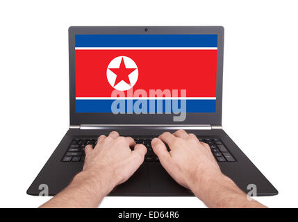 Mani lavorando su laptop che mostra sullo schermo la bandiera della Corea del Nord Foto Stock