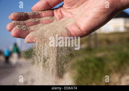 La sabbia che corre attraverso le mani sulla spiaggia Foto Stock