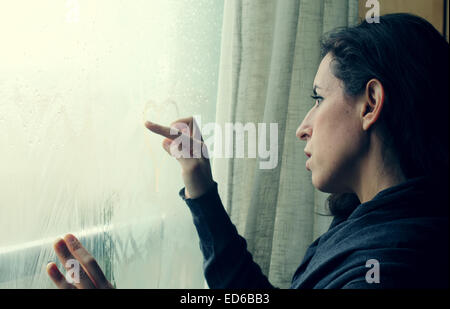 Metà donna adulta guardando fuori della finestra Foto Stock
