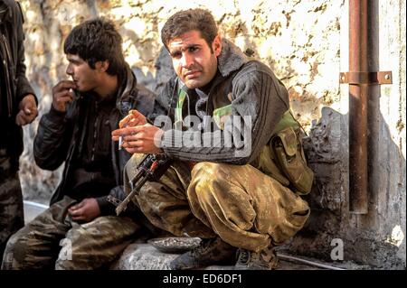 Kobane, Siria. Xxi Dec, 2014. In Kobane curdi ordinario, comprese le donne e i lavoratori anziani, sono rapidamente convertiti in condito dei veterani di guerra nelle strade e le rovine di quello che loro chiamano " il nostro Stalingrad''. Il combattimento è misurata in piedi; gli obiettivi sono edifici o anche camere in edifici. Gli edifici che sono ancora in piedi sono convertiti in rocche. Entrambi i lati sono bloccati in una lotta per la morte. I Curdi con ci torna contro la Turchia e di fronte a un nemico che nega loro la loro umanità, si è ritirata. © Gail Orenstein/ZUMA filo/Alamy Live News Foto Stock