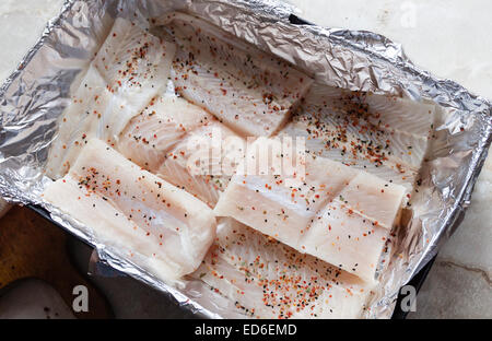 Merluzzo bianco crudo fresco filetto di pesce con erbe aromatiche sulla lamina di alluminio pronto a cuocere in forno, elevare view Foto Stock