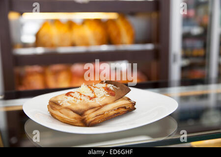 Pasta sfoglia con fetta di formaggio grattugiato su piastra bianca Foto Stock