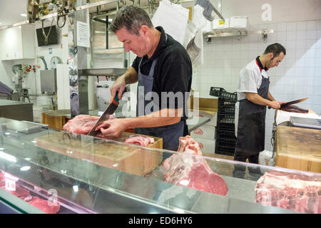 2 macellai wielding grandi coltelli slice tagli di agnello e fegato da pezzi più grandi di carni in Firenze Mercato Centrale Mercato Centrale Foto Stock