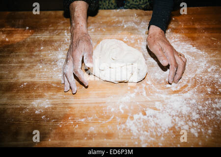 Le mani di grano per impastare la pasta di pane su una tavola di legno Foto Stock