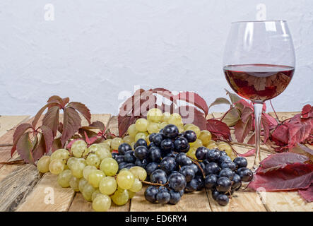Bicchiere di vino rosso con molti grappoli di uva Foto Stock