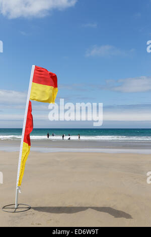 Il giallo e il rosso bandiera della vita delle guardie per contrassegnare il salvare parte di fistral beach in una giornata ventosa a Newquay, Cornwall, Regno Unito. Foto Stock