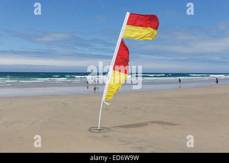 Il giallo e il rosso bandiera della vita delle guardie per contrassegnare il salvare parte di fistral beach in una giornata ventosa a Newquay, Cornwall, Regno Unito. Foto Stock