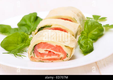 Lavash rotoli con salmone, formaggio ed erbe su piastra bianca Foto Stock