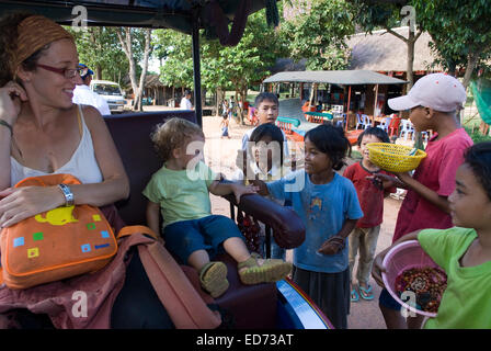 Viaggiare con bambini. Ragazzi la vendita di cartoline e souvenir a una madre a piedi con sua figlia. Preah Khan Temple. Preah Kha Foto Stock