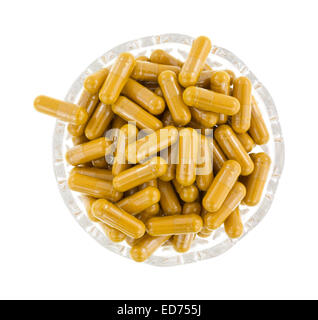 Vista dall'alto di un gruppo di curcuma capsule a base di erbe in una piccola ciotola di vetro su uno sfondo bianco. Foto Stock