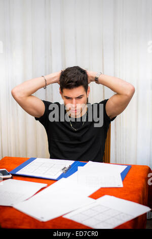 Triste o preoccupato per il giovane uomo di lavoro o di studio a casa Foto Stock