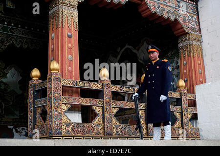 Una scentretta armata si erge ferma all'ingresso del Uffici governativi nella fortezza di Tashichho Dzong, sede del governo del Bhutan dal 1952 e attualmente ospita la sala del trono e gli uffici del re ai margini della città di Thimphu la capitale del Bhutan Foto Stock