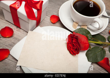 Cartolina sbozzato, una tazza di caffè e una rosa rossa sul tavolo Foto Stock