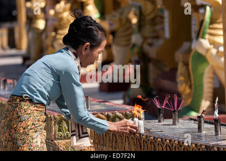 Donna locale accendendo candele, offerte sacrificali, Shwedagon pagoda, grande Dagon Pagoda o pagoda dorata, Yangon, Myanmar Foto Stock