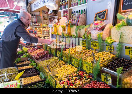 Negoziante vendita di verde e olive nere in vendita al mercato alimentare di Kadikoy district, lato Asiatico di Istanbul, est della Turchia Foto Stock