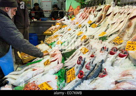 Negoziante la vendita di pesce fresco pesce bonito calamari al tuo pescivendolo nel mercato alimentare di Kadikoy district asiatica di Istanbul, est della Turchia Foto Stock