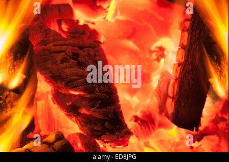 Bagliore calorosamente di un tradizionale scena invernale come un fuoco aperto in una casa irradia luce incandescente come brace di legno e carbone masterizzare hot Foto Stock