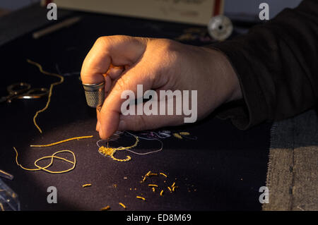 Una donna che ricama usando il filo d oro Foto Stock