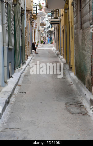 Scena di strada nel villaggio di Pyrgi, Chios, con una vecchia donna su un sedile Foto Stock