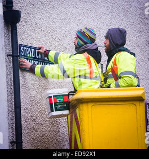 Due autorità locale (Ceredigion County Council) manodopera diretta ai lavoratori dipendenti in un 'cherry picker' sostituendo il segno sul Cambriano Street , Aberystwyth, con nuove versioni con "patrimonio" il carattere tipografico, Wales UK Foto Stock