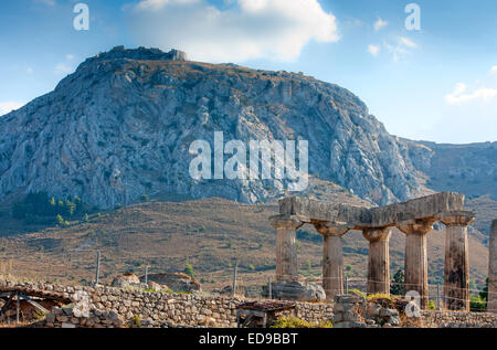 Tempio di Apollo a Corinto antico, con Acrocorinth in background, del Peloponneso, della Grecia Foto Stock