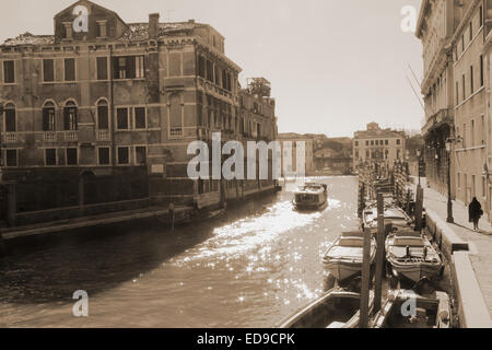 Un viaggio in barca attraverso i canali di Venezia come il sole che si riflette sull'acqua creando lampeggia e bagliori. La fotografia in Foto Stock