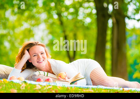 Brown-eyed ragazza con mele e un libro nel parco Foto Stock