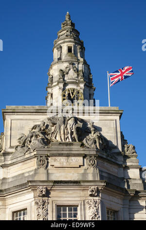 City Hall di Cardiff, Galles, UK. Le statue sulla facciata che rappresenta la poesia e la musica, sotto la torre dell orologio e la bandiera europea Foto Stock