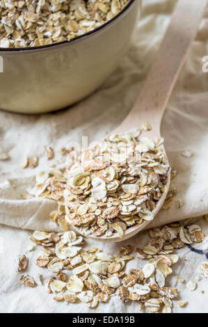 Fiocchi d'avena in un cucchiaio di legno e una ciotola di cereale Foto Stock