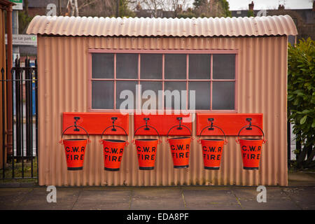 Sei red fire bucket appeso al di sotto di una finestra di un ferro corrugato capanna, Kidderminster Severn Valley Railway Station, Worcs REGNO UNITO Foto Stock