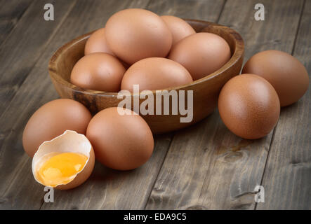 Le uova in una ciotola di legno sul tavolo da vecchie schede guaste guscio d'uovo e il tuorlo d'uovo Foto Stock