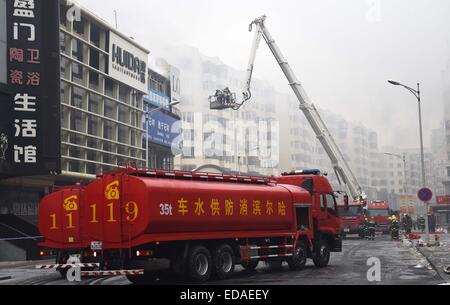 (150104) -- HARBIN, gen. 4, 2015 (Xinhua) -- aumento dei fumi da un magazzino bruciato a Beifangnanxun mercato della ceramica nel distretto Daowai, Harbin, capitale del nord-est della Cina di Provincia di Heilongjiang, gen. 4, 2014. Il magazzino blaze in Harbin City che ha ucciso 5 i vigili del fuoco non è ancora stato completamente spento, i vigili del fuoco locali detto Domenica. Al 10:40 a.m. Domenica, un edificio residenziale accanto al magazzino era ancora fumante. Soccorritori ha detto che la fonte del fuoco è stata difficile da determinare a causa della costruzione di una struttura complicata, e l'edificio è a rischio di collasso. Foto Stock