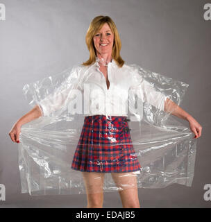 Donna che indossa un vedere attraverso il poncho di plastica come protezione da vento e pioggia Foto Stock