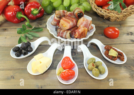 Tapas farcito con prugne secche, fichi e albicocche e pancetta sul piatto di legno Foto Stock