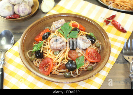 Spaghetti alla puttanesca con olive, capperi e acciughe su un tovagliolo Foto Stock