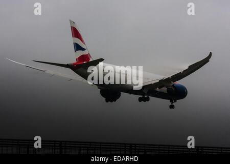 Il 3 gennaio 2015, l'aeroporto di Heathrow di Londra. Basse nubi e pioggia offrono le condizioni ideali per osservare la scia dei vortici e 'pelosità' come l'umidità si condensa sulle ali di aerei di atterraggio. Con la pista visibile solo all'ultimo minuto, vari piani dovevano eseguire un 'go-round", abbandonando i loro primi tentativi di terra. Nella foto: un British Airways Boeing 787 Dreamliner si prepara a terra su Heathrow la pista 27L Foto Stock