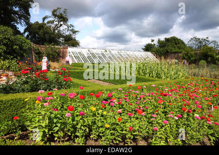 Un giardino con fiori e una grande serra dietro. Foto Stock