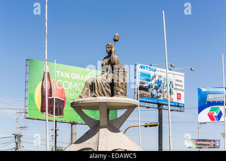 Strada la statua di una donna seduta in Arequipa all inizio del Canyon del Colca, Perù, nel mezzo della strada di fronte a cartelloni pubblicitari Foto Stock