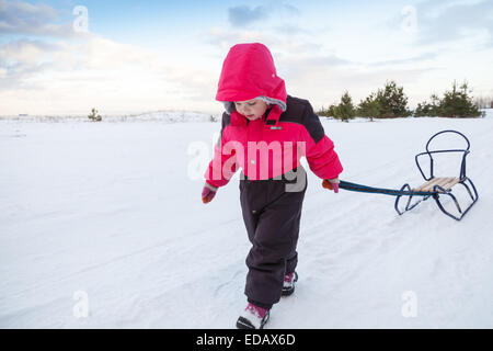 Little Baby girl in rosa tirando una slitta in inverno nevoso road Foto Stock