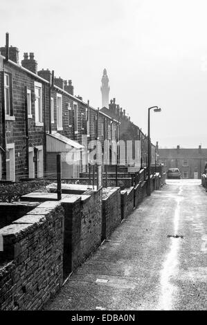 Una piovosa giornata bagnato nello Yorkshire che mostra una tipica a schiera vittoriana strada che conduce verso una follia denominata Victorian Wainhouse Tower Foto Stock