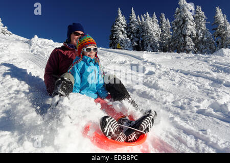 Madre e figlia slittino sulla neve in montagna, Hurricane Ridge, Clallam County, il Parco Nazionale di Olympic, Washington, Stati Uniti d'America Foto Stock