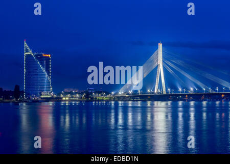 Ponte Vanšu, cavo-alloggiato bridge, crepuscolo, blu ora, oltre il fiume Daugava o Western Dvina, con la Swedbank building, Riga Foto Stock