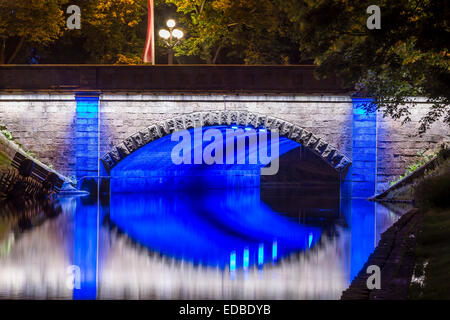 Ponte illuminato lungo il canale Pilsetas, Riga, Lettonia Foto Stock