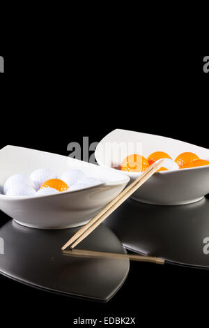 Due ceramiche bianche bocce con palline da golf sul tavolo di vetro Foto Stock