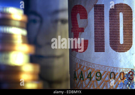 Ritratto di close-up di dieci pound note e una pila di Britsh sterling monete. Foto Stock