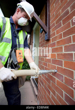 Immagine illustrativa della parete di cavità di isolamento. Un lavoratore di totale isolamento tubi soluzioni Rockwool in una cavità della parete. Foto Stock