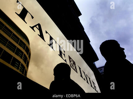 Una guardia di sicurezza sorge nella parte anteriore del logo di Tate & Lyle sul fascade dell'ufficio dell'azienda edificio sul Lower Thames Street, Londra Foto Stock